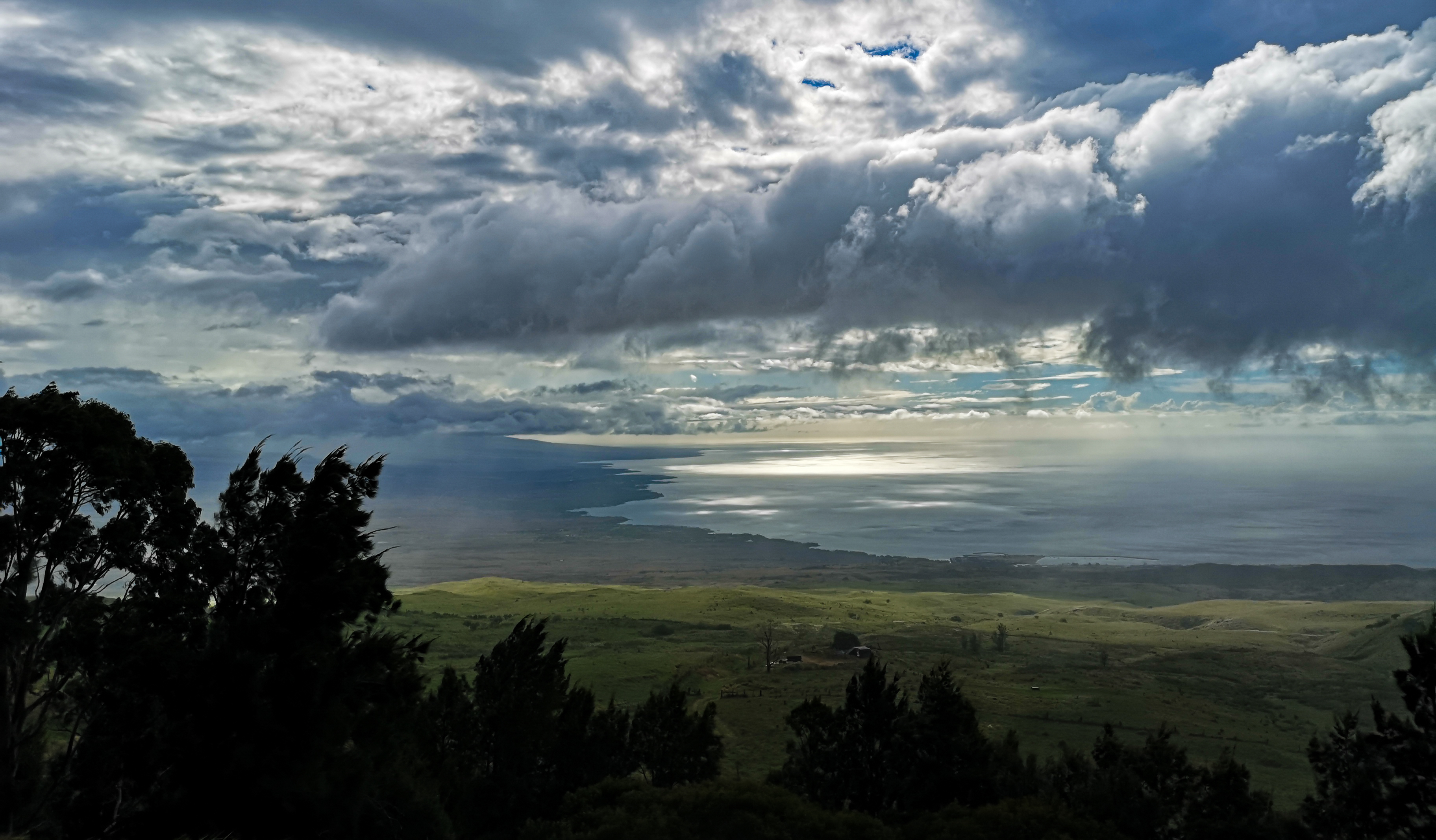 rain clouds over some hills and a beach in hawaii